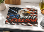 Glass cutting board with American flag design and '250 Years of Freedom' text on a kitchen counter.