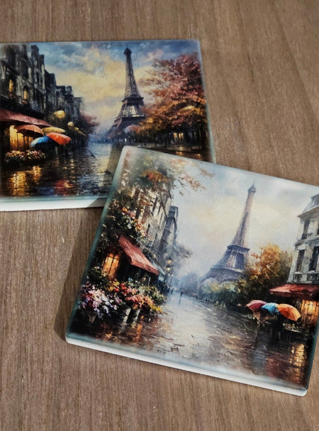Two glass coasters with Paris-themed artwork featuring the Eiffel Tower on a wooden surface.